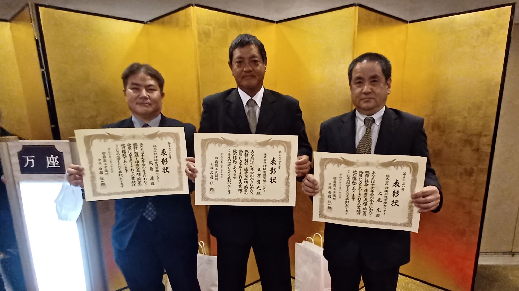 弊社社員3名が表彰状を掲げている写真
